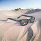 The KD's 2019 sunglasses ideal for outdoor activities with grey polarized lenses laid on the sand in the desert.