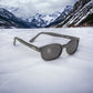 KD's 21120 sunglasses that fit under a motorcycle or ski helmet. Worn by SAMCRO bikers and Jax Teller in Sons of Anarchy. With a sleek matte black frame and smoked lenses. Posed in the snow in the mountains.