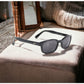 KD's readerz sunglasses with correction index. Worn by Jax Teller in Sons of Anarchy. With elegant black frames and dark grey lenses. Sitting on a comfortable couch.