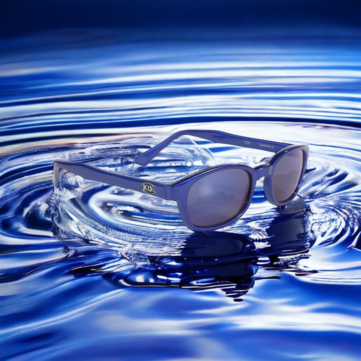 X-KD's 10122 large sunglasses for sportsmen and bikers with a blue metallic frame and blue polycarbonate mirror lenses set on water.